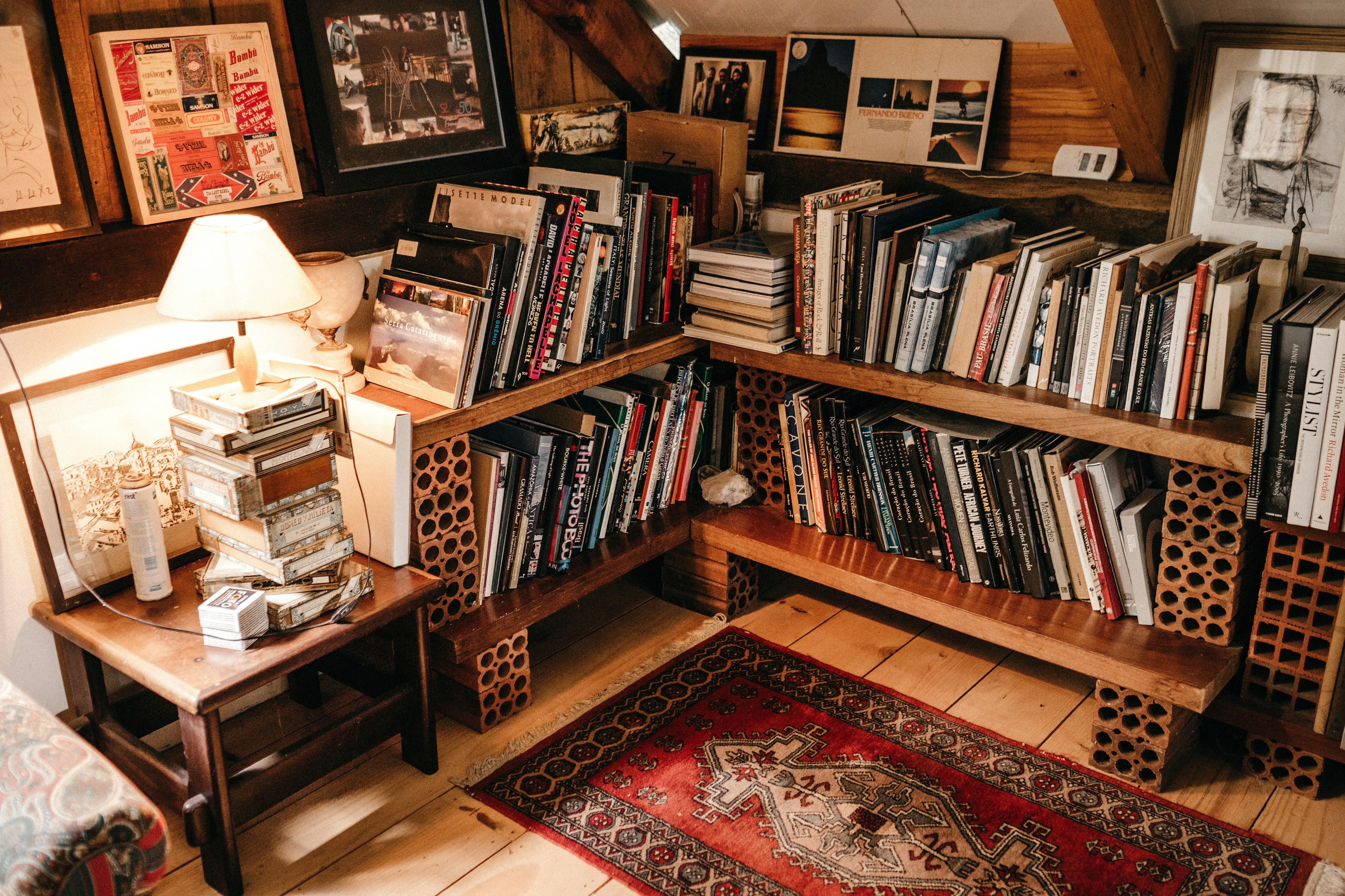 assorted books in shelf near lighted table lamp